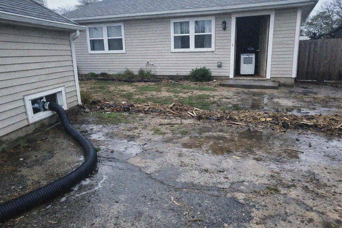 Storm water flowing across the front yard and driveway of a detached house on Staten Island during heavy rain