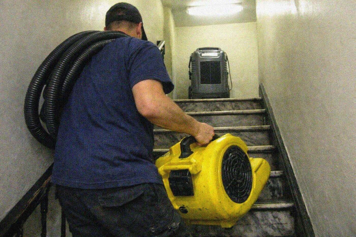 An air mover being carried up the stairwell of a New York walk-up apartment building