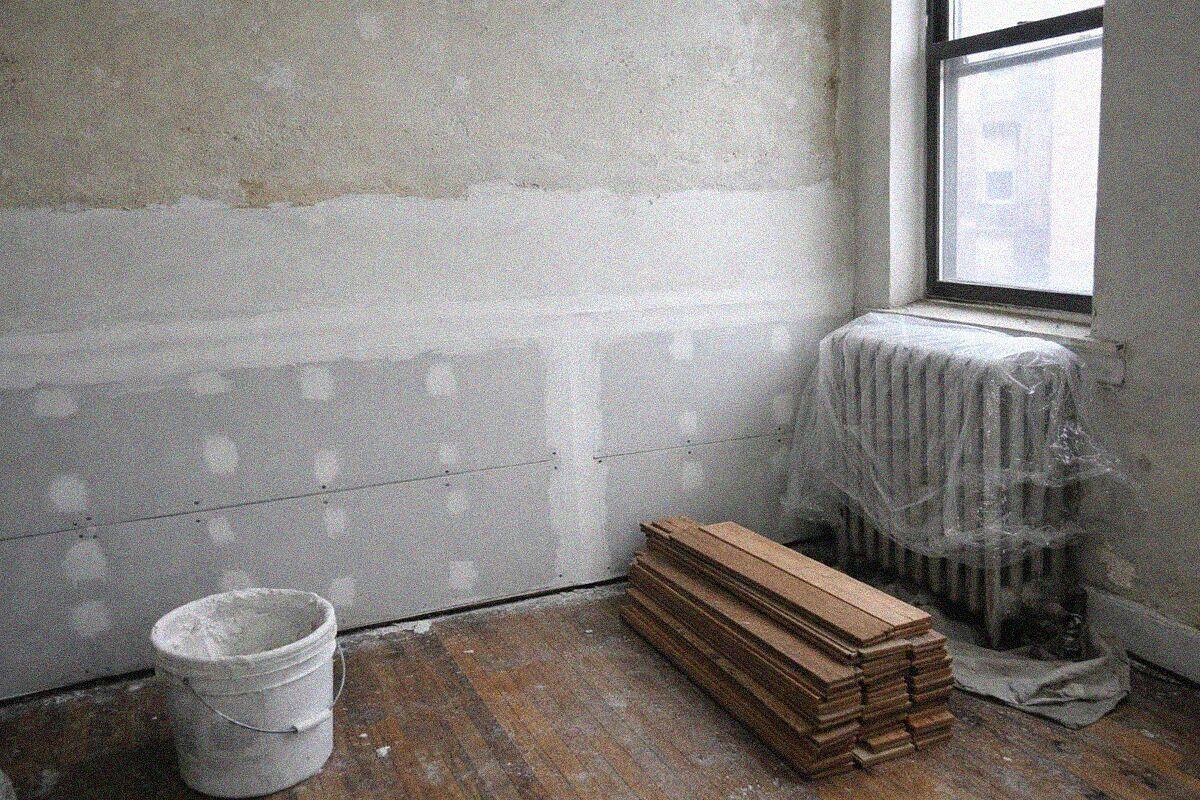 New drywall and a fresh plaster skim coat on the lower wall of a New York apartment after water damage repair